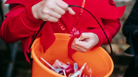 Frightfully Fun- Celebrate. a kid holding an orange pail of candy